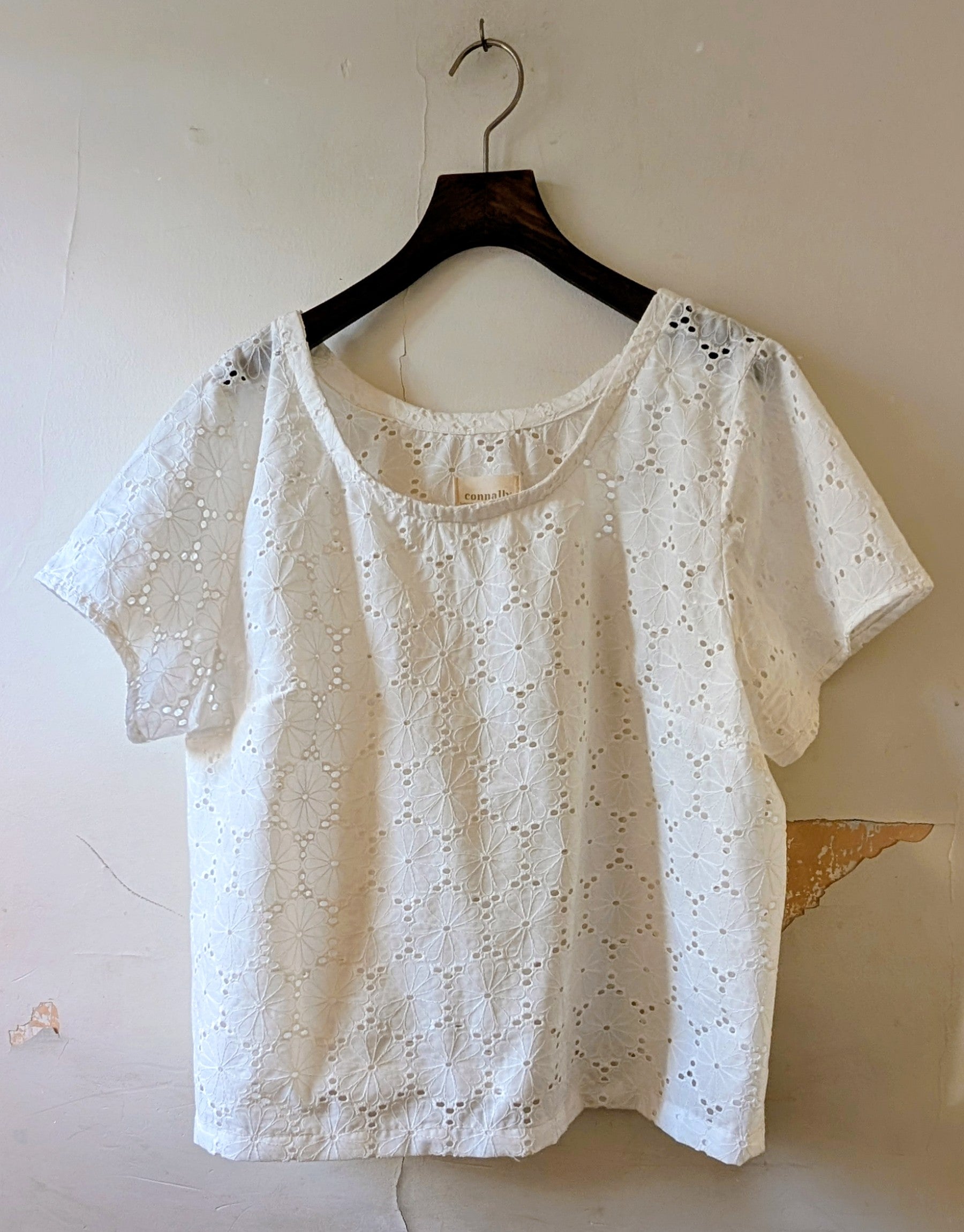 White lace top on a hanger against a plain background