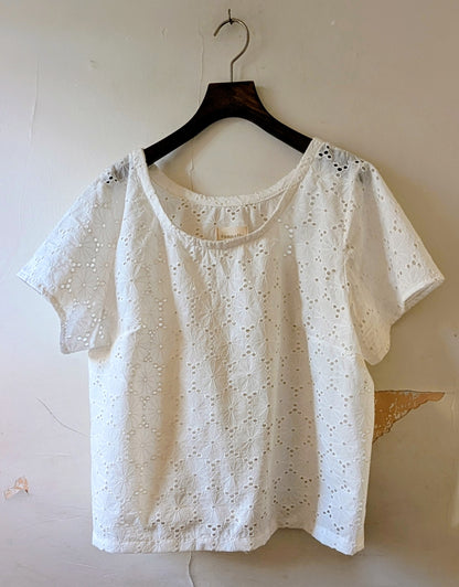 White lace top on a hanger against a plain background